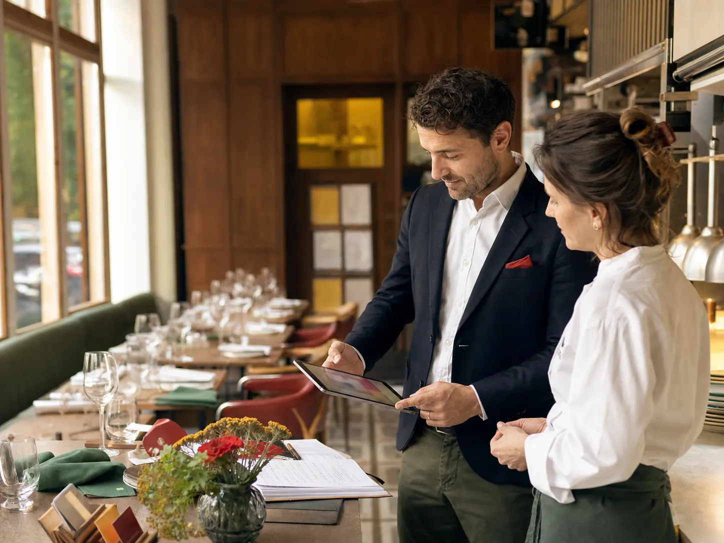 Responsable de restaurant et cheffe consultant une tablette avant le service