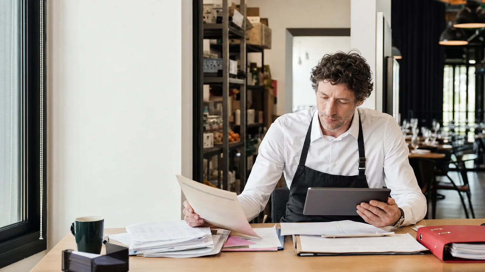 Responsable de restaurant contrôlant une facture fournisseur avec une tablette